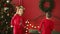 Joyful siblings kid boy and little girl wearing pyjamas jumping on bed on background of christmas tree on xmas holidays