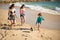 Joyful sisters and brother playing at beach