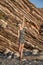 A joyful slender girl in a dress stands on the coastal cliffs