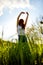 joyful slender woman posing in a field with her arms raised high