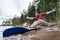 Joyful, smiling man is resting on the shore of the lake after a kayak trip, he spread arms out to the sides and enjoys