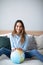 Joyful smiling woman indoors with a globe looking at the camera