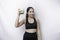 Joyful sporty Asian woman wearing sportswear with glass of tasty green smoothie, isolated on white background