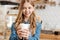 Joyful teenage barista warming hands around a coffee cup