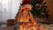 A joyful teenage girl sits next to the New Year tree and plays with a garland, untangles it for decoration. New Year and