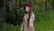 Joyful teenager girl in coat and beret holding ripe apple in hand at fruit garden. Happy young girl with apple in hand