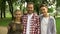 Joyful teenagers and their father showing thumbs up into camera at park, family