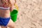 Joyful three-year-old girl plays with a bucket and shoulder blade in the sand on the beach