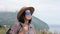 Joyful travel woman in straw hat sunglasses walking on top of mountain admiring natural seascape