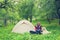 Joyful traveler plays with large shepherd dog next to the tent