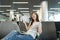 Joyful traveler tourist woman working on laptop, holding bundle of dollars cash money, spreading hands wait in lobby