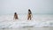 Joyful wet girls in swimwear fooling, having fun at the sea surf waves. Attractive female friends play splashing water