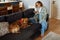 Joyful white woman using cellphone while sitting on sofa with her dog