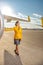 Joyful woman airline worker standing near aircraft at airfield