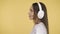 Joyful woman is calmly dancing. Energetic middle-aged woman in headphones on yellow background dancing