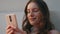 Joyful woman holding smartphone at home closeup. Serene girl dreaming replying