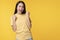 Joyful woman successful with excitement up, keeps hands raised arm while standing over isolated yellow background