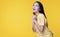 Joyful woman successful excitement up with keeps hands raised arm while standing over isolated yellow background