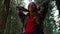 Joyful woman taking break during hike in woods. Smiling girl standing in forest