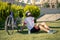 Joyful young bearded cyclist sitting on grass