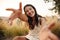 Joyful young caucasian woman smiles with teeth, stretches hands to camera, rests in countryside.