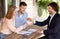 Joyful young family receiving key to their new house from real estate agent, outdoors