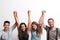 Joyful young group of friends standing in a studio, lifting hands.