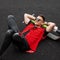 Joyful young man model in a fashionable denim vest in black jeans in sunglasses enjoys a rest lying on the pavement. American guy