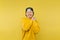 Joyful young man in a yellow sweatshirt stands on a yellow background with a happy face and closed eyes