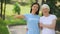 Joyful young woman and aged lady pointing at volunteer word on t-shirt, charity