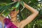 Joyful young woman behind palm leave smiling enjoy in vacation wearing colorful dress necklace and earrings Jamaica