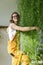 Joyful young woman gardener standing on a stepladder, embracing lush asparagus fern houseplant. Love of plants.Indoor garden