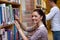 Joyful young woman looking for a book