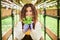 Joyful young woman with plant standing in greenhouse.