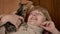 Joyful young woman in sweater lying on sofa with tabby kitten indoors close up low angle view