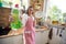 Joyful young woman wearing an apron standing in the kitchen holding dish washing detergent and celan plate, feeling satisfied