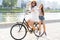 Joyful young women riding a bicycle together. Best friends having fun on a bike at the river promenade in the cit.