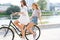 Joyful young women riding a bicycle together. Best friends having fun on a bike at the river promenade in the cit.