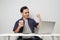 joyfull happy asian man at workplace while sitting in front of laptop computer. on isolated background