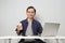 joyfull happy asian man at workplace while sitting in front of laptop computer. on isolated background