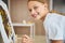 Joyous blonde girl painting on the easel