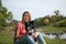 Joyous brunette playing with with her white and black dog in the park during sunny summer day outdoors.