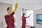 Joyous female cleaner and her colleague cleaning living room