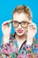 Joyous Girl in Eyeglasses is Posing in Studio Looking at the Camera. Portrait of Funny Blonde Woman with Ponytail