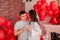 Joyous moment between young couple celebrating with toast Valentines day near red balloons