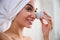 Joyous young woman using a face massager after shower