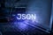 JSON inscription against laptop and code background. Technology concept