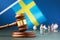 Judge gavel against the background of a blurry flag and toy plastic men, the concept of litigation in Sweden