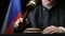 Judge with gavel in his hand hammering against Russian flag and black background in court room