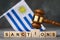 Judge gavel, wooden cubes with the text on the background of the flag of Uruguay, concept on the topic of sanctions in Uruguay